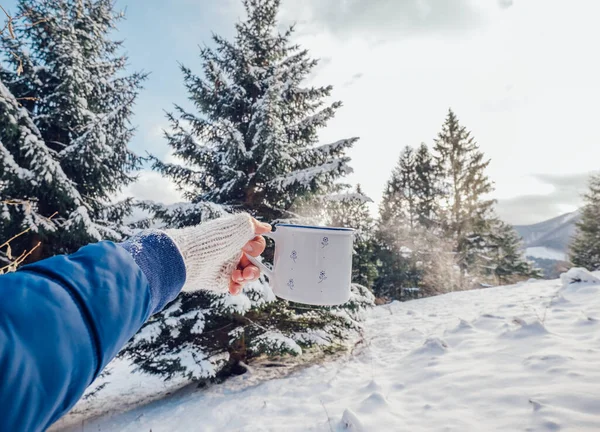 男手で編むミトンで熱いお茶のカップとともに雪の森の背景 — ストック写真