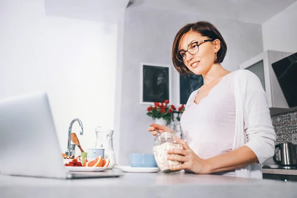 Kvinna Förbereda Frukost Och Titta Nyhet Laptop — Stockfoto