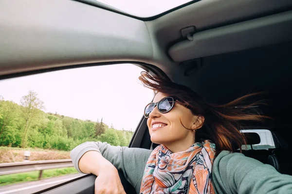 空飛ぶ髪の女性は車の窓から見る — ストック写真