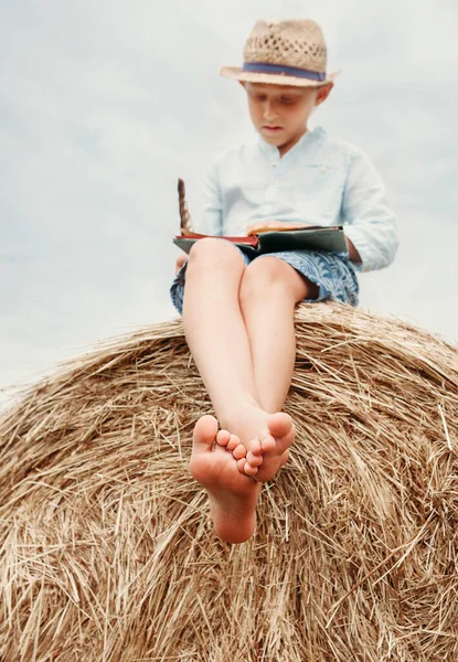 Barfüßiger Junge Liest Buch Sitzt Auf Heuhaufen — Stockfoto