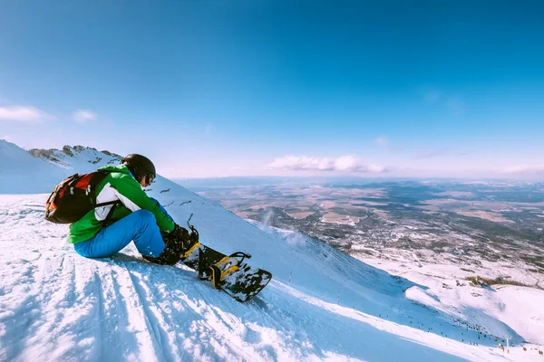 Snowboarder Στερεώνει Snowboard Πόρπες Κάθεται Στην Κορυφή Του Λόφου Χιόνι — Φωτογραφία Αρχείου