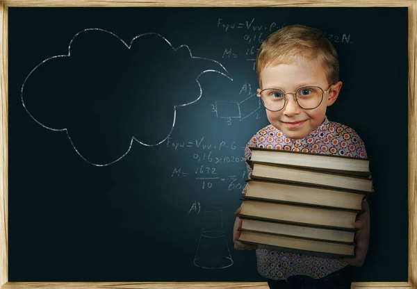 学校の黒板の近くに本を持つ男の子 — ストック写真