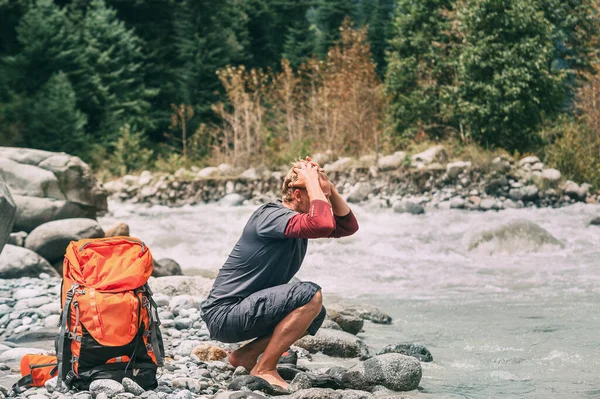 若い男の観光客山の川の水でリフレッシュ — ストック写真