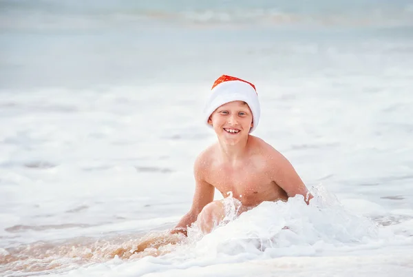 Glimlachende Jongen Hoed Van Kerstman Zwemt Oceaan Surflijn Kerstmis Nieuwjaarsvakantie — Stockfoto