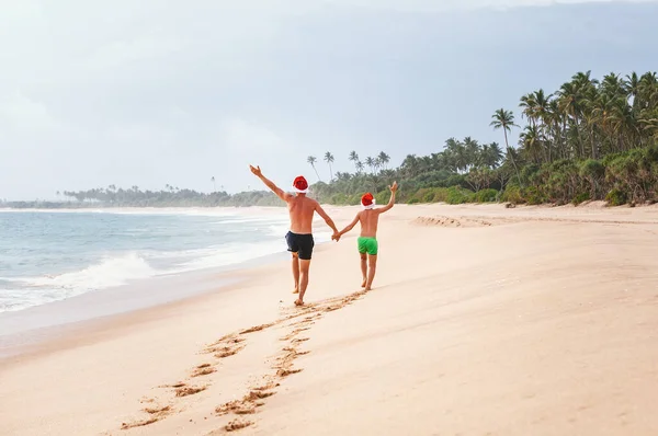 Vater Und Sohn Weihnachtsmützen Laufen Perfekten Sandstrand Der Tropischen Insel — Stockfoto