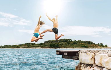 Baba ve oğul Adriyatik kıyılarında keyifli bir tatil yapıyorlar. Tekne iskelesinden feragatnamelere atlayan mayo giyiyorlardı. Aile zamanı, çocukluk ya da babalık konsepti.