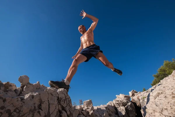 조깅을 흘리며 속도로 달리는 근육질 선수가 갈라진 절벽을 넘는다 사람들은 — 스톡 사진