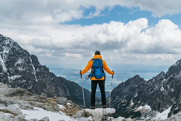 Slovakya 'nın High Tatras kentindeki dağ yürüyüşü sırasında dağ vadisi manzarasının tadını çıkaran parlak turuncu ceketli sırt çantalı adam. Etkin insanlar konsepti