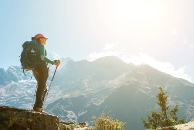 Yüksek iklim yürüyüşü sırasında dağ manzarasının tadını çıkaran yürüyüş direkleri kullanan genç bir gezgin kadın. Everest Merkez Kampı 'nın yürüyüş rotası, Nepal. Etkin tatil konsepti resmi