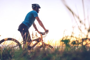 Erkek motorcu şehrin tepesinde gün batımıyla karşılaşır. Aktif spor insanları konsepti imajı