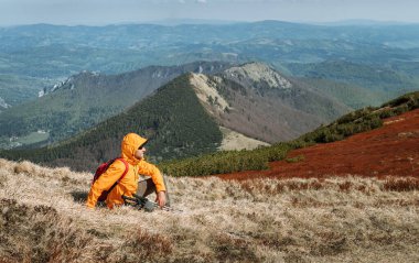 Slovakya 'nın Mala Fatra Dağları' ndaki yeşil vadide yürüyüş direkleri olan parlak turuncu ceketli gezgin. Aktif insanlar ve Avrupa yürüyüş konsepti imajı.