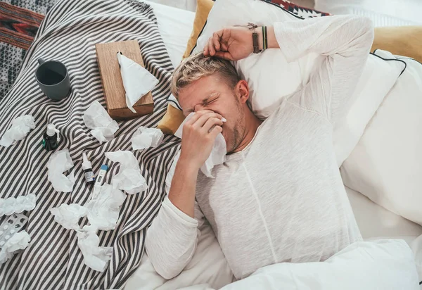 Нездоровый Уставший Человек Чихает Вытирает Сопливый Нос Мужчина Лежит Уютной — стоковое фото