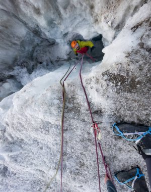 Kurtarma operasyonu sırasında buzul yarığından yükselen canlı renkler içinde dağcı, aşırı spor meraklıları, yüksek rakımlı dağcılık, macera, açık hava, aşırı aktivite konsepti.