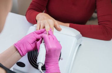 Manikür uzmanının, ojeyle oje sürme aletini, güzellik salonunun kişisel bakımını, küçük işletme konseptindeki sağlıklı tırnak bakımını ve günlük iş akışını kullanarak tırnaklarını titizlikle şekillendirme fotoğrafını çek.