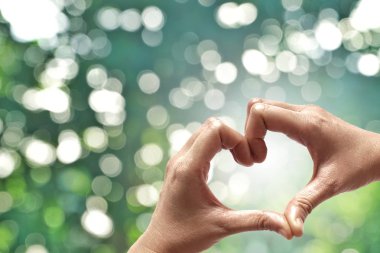 Eller şekil doğa yeşil bokeh güneş ışık parlama üzerinde kalp ve yaprak arka plan bulanıklık. Sevgililer günü, sevgi işareti, el hareketi kavramı.                                              