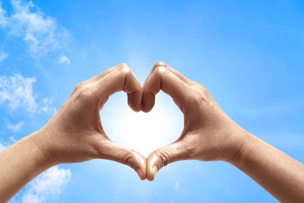 Woman hold hands up to sky in the shape of love heart on nature sun light flare and cloud with blue sky background.Valentine\'s day,Sign of Love,Hand gesture Concept.