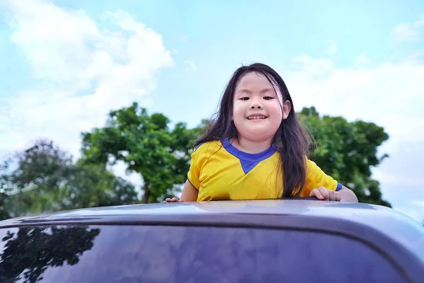 Adorable Asian Little Girl Standing Sunroof Car Cloud Tree Blue — стоковое фото