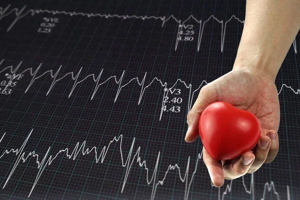 Man holding red heart in hand with heartbeat graph.Sign of Heartache,Suffering from chest pain,Heart attack or painful cramps, pressing on chest with painful expression.