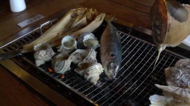 Çeşitli türlü ızgara deniz kabukları scallop(Hotate), boynuzlu türban deniz salyangoz (Sazae) ve Wakayama balık pazarı, Japan.Roasted balık duman ile sıcak ızgara balık.