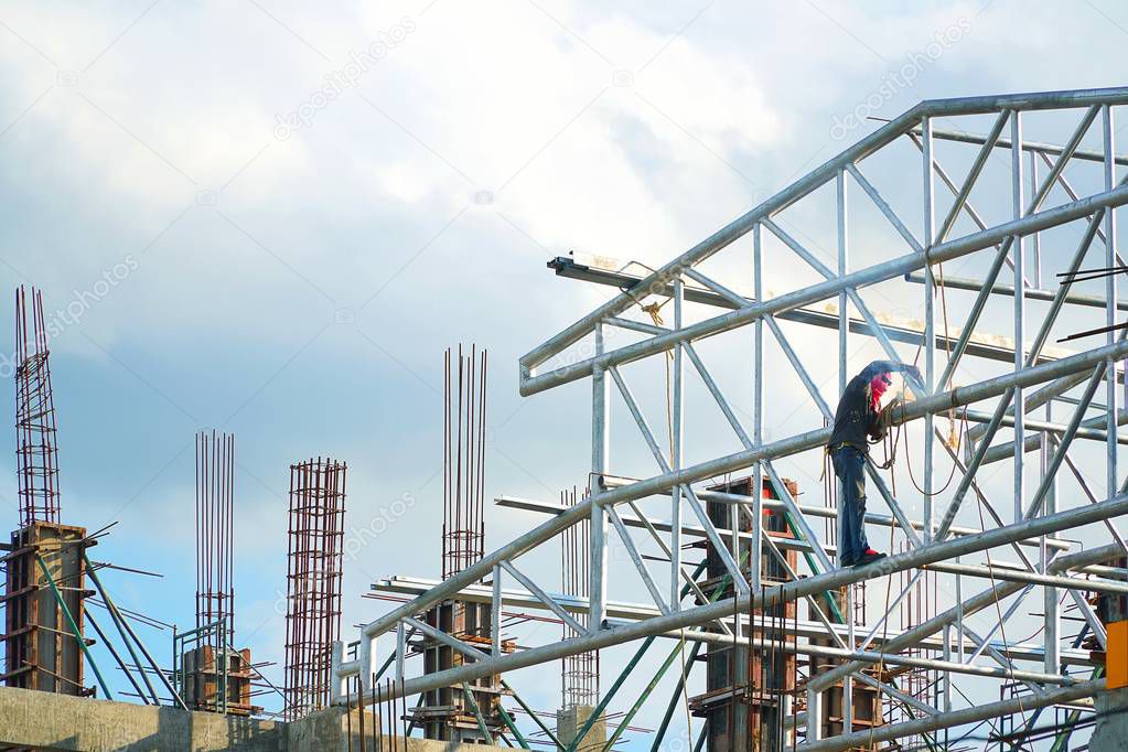 Construction industry of Engineer Business Concept with worker standing and working on building from high ground and steel rod at Construction site on blue sky and clouds background.
