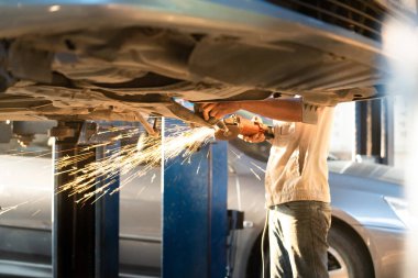 Tamirci garajda ya da araba servisi merkezinde çalışıyor ve araba fren diskini tamir ediyor. Makinenin alt kısmında bulunan mobil metal parçası. Modern araç motoru, sanayi, mekanik ve iş dünyası kavramı.