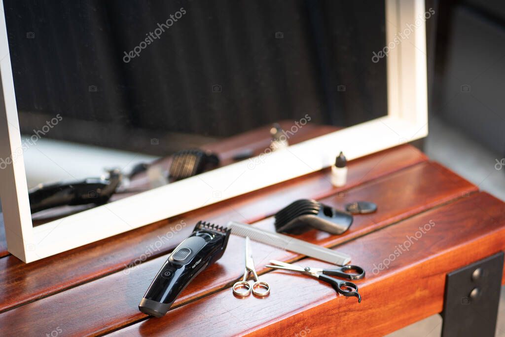 Set of cutting tools for cutting hair at barbershop beard salon.Hair accessories such as Clippers and Comb on wooden desk table in a professional hairdresser barber.Stay home,Safe life.