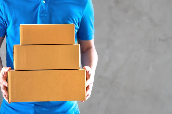 Delivery service courier man employee in blue t-shirt uniform holding empty cardboard boxes or parcel in hand.Copy space.Fast and free Delivery transport.Business Online shopping and Express delivery.