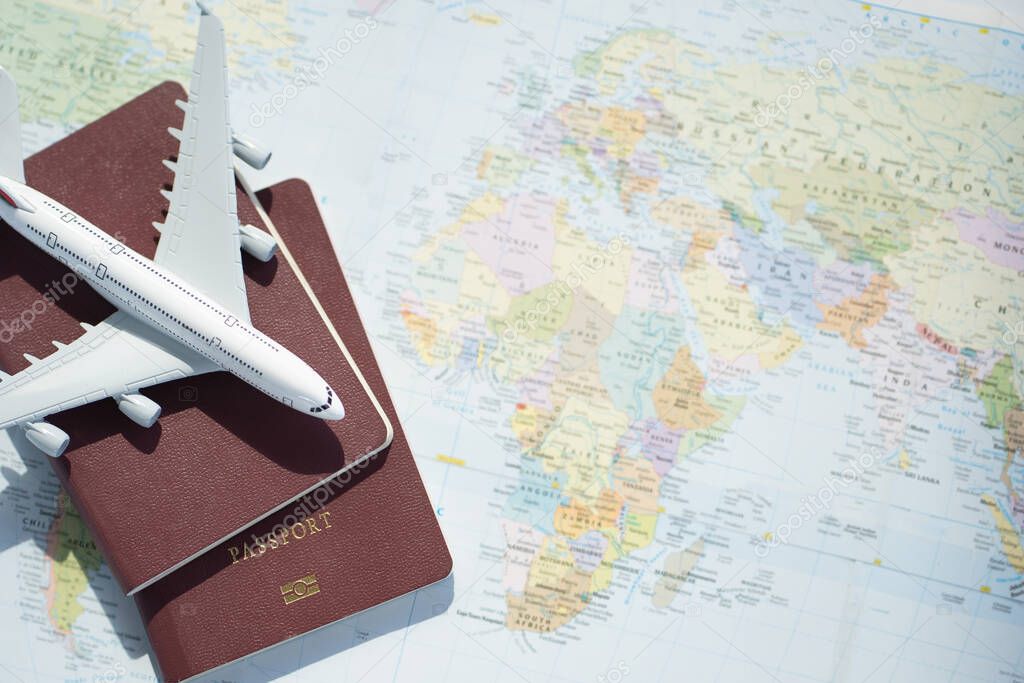 Passport with a map background.Travel planning.Top view of traveler accessories with a plane  on world map.Preparation for travel.Traveling Journey Vacation Holiday concept.