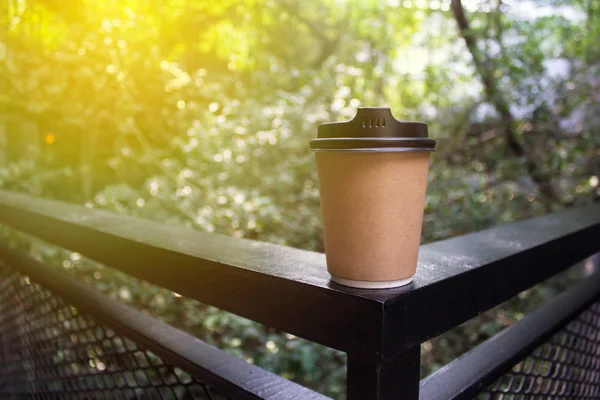 Blur background nature landscape panorama view from railing panel inside shopping mall with brown coffee recycle paper cup. Ray by sunlight