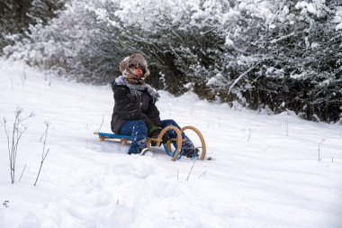 Karlı ülke, bir kızak üzerinde oturan çocuk