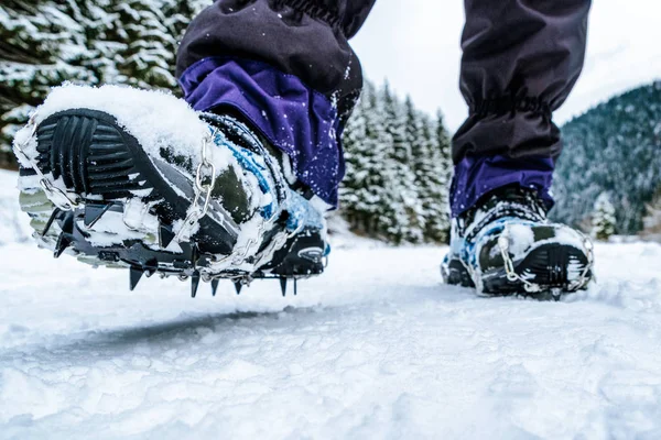 Crampons on hiking boots. Close up view on shoes on snowy path