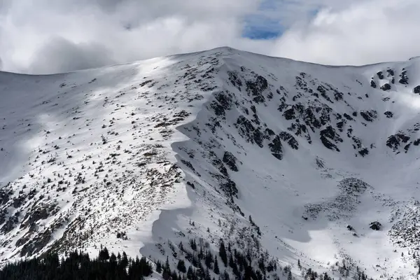 Snowy hills and clouds on the sky Stock Image