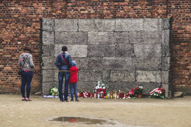 Auschwi toplama kampında ölüm duvarı önünde Ziyaretçiler