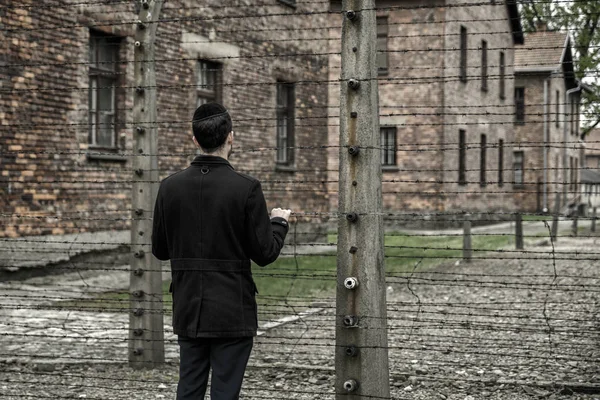 Еврей смотрит через колючую проволоку в концентрационном лагере Освенцим , — стоковое фото