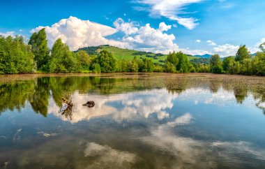 Su yüzeyindeki bulutların yansıması. Slovakya 'daki Parnicke Rybniky Gölü