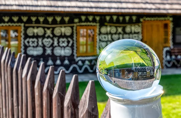 レンズボールの伝統的な木造コテージの反射 ファサード上の典型的な装飾品を持つ村Cicmany スロバキア — ストック写真