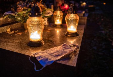 Mezarlıktaki mezarlıkta koruyucu maske ve fenerler. Coronavirus Covid-19 kurbanları