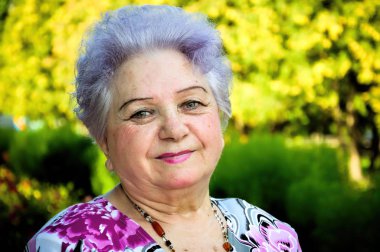 Park bitki örtüsü nün arka planında yaşlı kadın