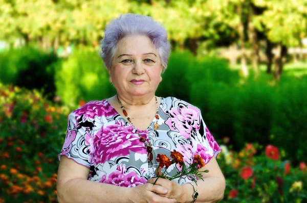 Пожилая женщина на фоне парковой растительности Стоковое Изображение