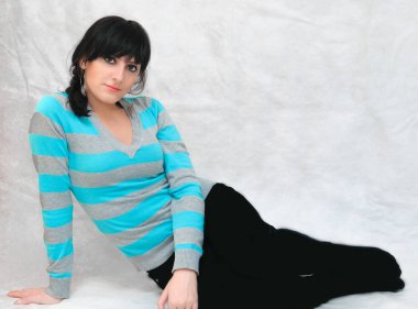 Genç güzel bir kadının portresi, minimal makyaj, doğallık ve güzellik ile pürüzsüz sağlıklı bir cilt. Yerde oturan gri bir arka plan üzerinde Büyüleyici esmer.