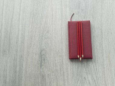 Ofis aksesuarları: kırmızı bir not defteri ve ahşap gri masa üzerinde kırmızı kalem. Üstten Görünüm, kopya alanı
