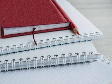 Boş notebooklar, kırmızı defter ve ahşap gri masada kırmızı bir kalem. Okula dönüyoruz. Üst görünüm. Boşluk Kopyala
