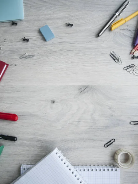 Papelería: bolígrafos, lápices, marcadores, botones, clips, borradores, cuadernos, cinta adhesiva en un escritorio gris de madera. Vista superior. Copiar espacio Imagen De Stock