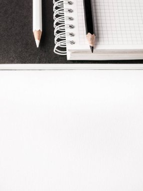 Ofis konsepti. Beyaz Kağıt arka planda siyah ve beyaz kalemler, boş defter ve siyah dergi. Üst görünüm. Boşluk Kopyala