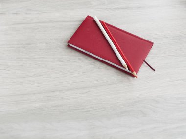 Ofis aksesuarları: kırmızı bir not defteri, beyaz bir kalem ve ahşap gri bir masada kırmızı kalem. Okula dönüyoruz. Üst görünüm. Boşluk Kopyala
