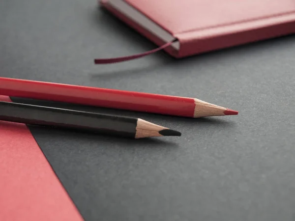 Accesorios de oficina: bloc de notas rojo, lápiz negro, lápiz rojo sobre fondo negro. Vista superior —  Fotos de Stock