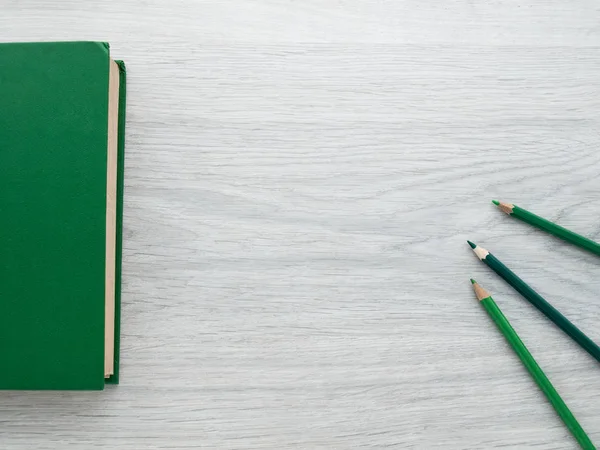 Training and development: Green book and green pencils on a wooden gray table. Education. Business. Top view. Copy space