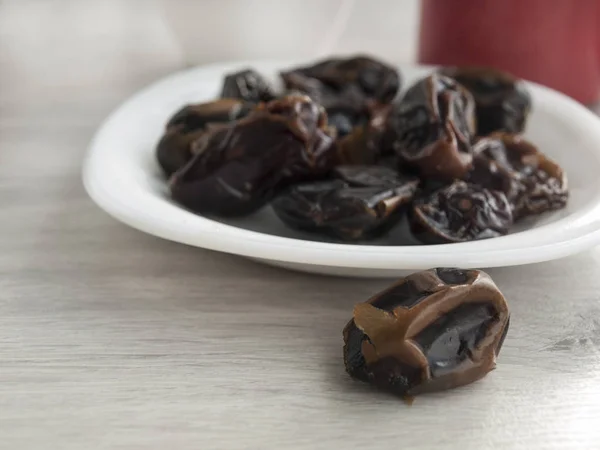 Healthy food: dried dates close-up on a saucer, red cup, white cup on a wooden gray table. Top view