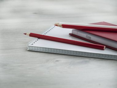 Ofis aksesuarları: kırmızı bir not defteri, beyaz bir not defteri ve tahta gri masada kalem. Okula dönüyoruz. . kaybetmek-up. Üst görünüm. Boşluk Kopyala