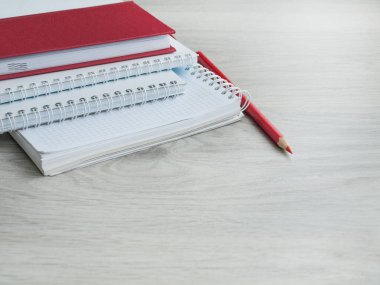 Boş notebooklar, kırmızı defter ve ahşap gri masada kırmızı bir kalem. Okula dönüyoruz. Üst görünüm. Boşluk Kopyala